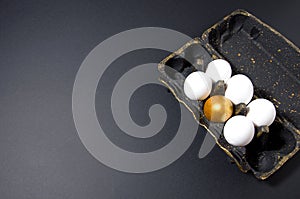 Black egg stand with gold stands on a black background, in the stand are white and one golden egg, horizontal background,