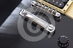 Black electric guitar bridge close-up macro, black body