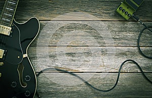 Black electric guitar, effect pedal on a rustic wood