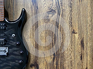 Ã Â¸Â´black electric guitar made from quilted maple top Popular musician on veneer brown wood background with copy space on right for