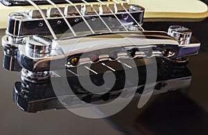 Black electric guitar with steel bridge, close-up macro, black body