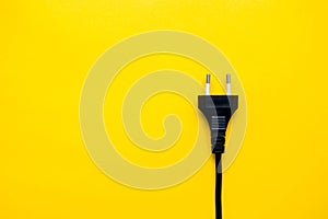 Black electric plug connector on yellow background. Top view. Copy, empty space for text