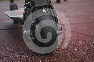 black electric scooter standing on the rubber pad in the park, rear in front