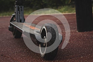 black electric scooter standing on the rubber pad in the park, rear view