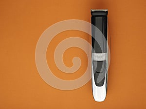 Black electric trimer on an orange-brown background.