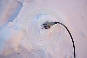 Black electric wire from the device lies on the snow photo