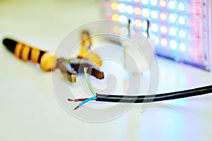 Black electrical wire with brown blue and green-yellow wires, pliers flashlight