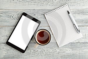 Black electronic tablet,paper notebook and a Cup of tea or coffee on a vintage shabby white wooden background. the view from the