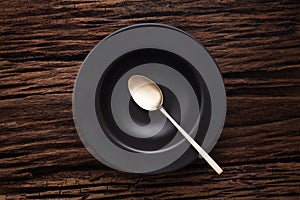 Black empty bowl spoon on wooden table background