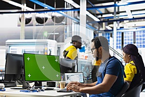 Black engineer adjusting robotic arm settings through chroma key display