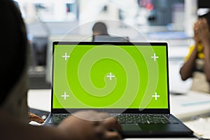 Black engineer adjusting robotic arm settings through chroma key display