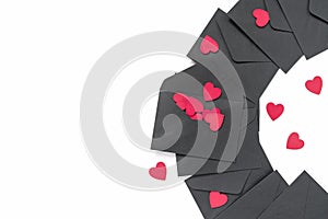 Black envelopes are decorated with red wooden heart shapes. Abstract background for Valentine`s Day. Flat lay. Top view