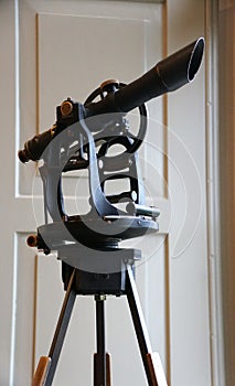 A black equipment transit with a compass and telescope to measure land grants, normally used by a surveyor
