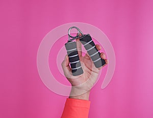 Black espander in female hand on pink background