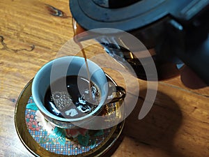 Black espresso coffee in a golden glass, eaten in a garden at home in Thailand, has a bitter taste, refreshing, very tasty.