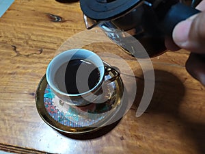 Black espresso coffee in a golden glass, eaten in a garden at home in Thailand, has a bitter taste, refreshing, very tasty.