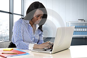 Black ethnicity woman sitting at computer laptop desk typing concentrated working