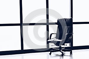 Black executive leather chair in empty office space with large window