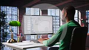 Black IT expert looking at user interface on computer at home office