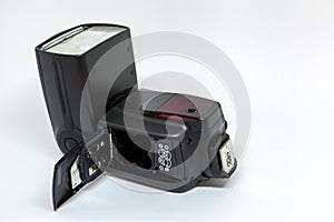 Black external flash for a camera with an open battery compartment.
