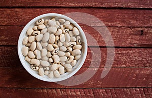 Black eyed beans in bowl on wooden background