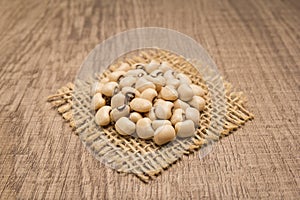 Black Eyed Pea legume. Grains on square cutout of jute. Wooden t