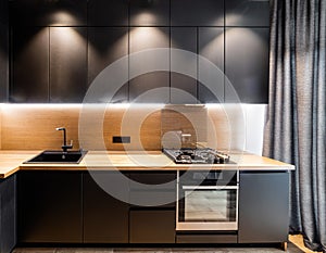 Black facades for new loft-style kitchens with a wood countertop with lighting