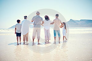 Black family, beach or holding hands with children, parents and grandparents standing in the water from behind. Back