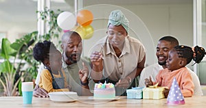 Black family, birthday cake and candles for children to celebrate with parents at a table. African woman, men and happy