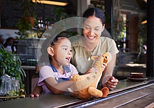 Black family, coffee shop or stuffed animal with a mother and daughter sitting in the window of a restaurant together