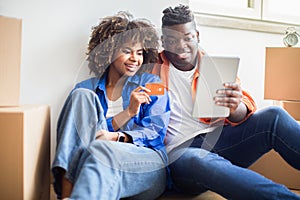 Black Family Couple With Digital Tablet And Credit Card Choosing Furniture Online