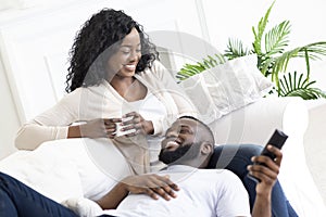 Black family couple relaxing on sofa, spending time at home.