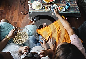 Black family eating popcorn while watching movie at home