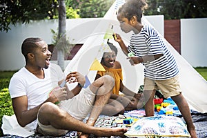 Black family enjoying summer together at backyard blowing soap b