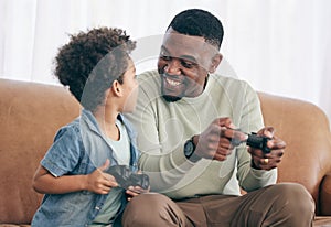 Black family, father and child playing video games on living room sofa together with controllers at home. Happy African