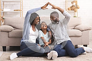 Black family making symbolic roof of hands above little girl