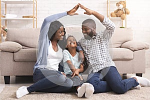Black family making symbolic roof of hands above little girl photo