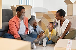 Black family sitting with cardboard boxes during moving house