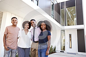 African American  family stand looking to camera in front of their modern home,close up