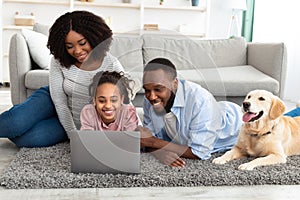 Black family using pc relaxing with dog at home