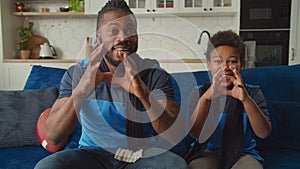 Black family watching American football on tv, celebrating successful reception