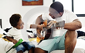 Black father enjoy playing guitar with his child together happiness