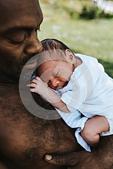 Black father holding his sleeping mixed race baby boy