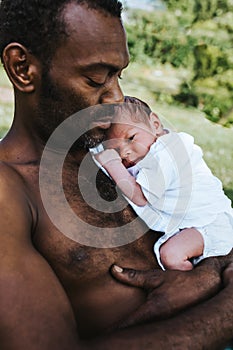 Black father holding his sleeping mixed race baby boy close