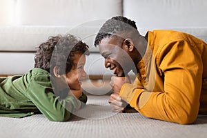 Black father and son enjoying playful moment together on floor