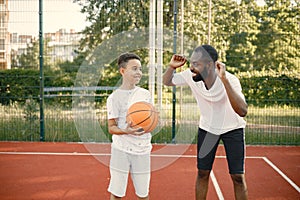 Black father with son playing basketball in basketball court together