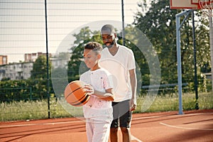 Black father with son playing basketball in basketball court together