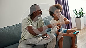 Black father and son playing video game on sofa