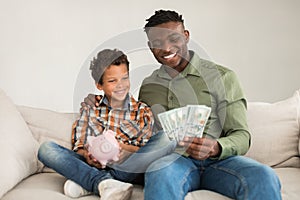 Black Father And Son Posing With Piggyback And Cash Indoor