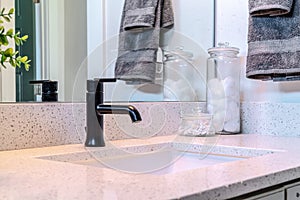 Black faucet and single ceramic sink on the clean bathroom vanity of a home